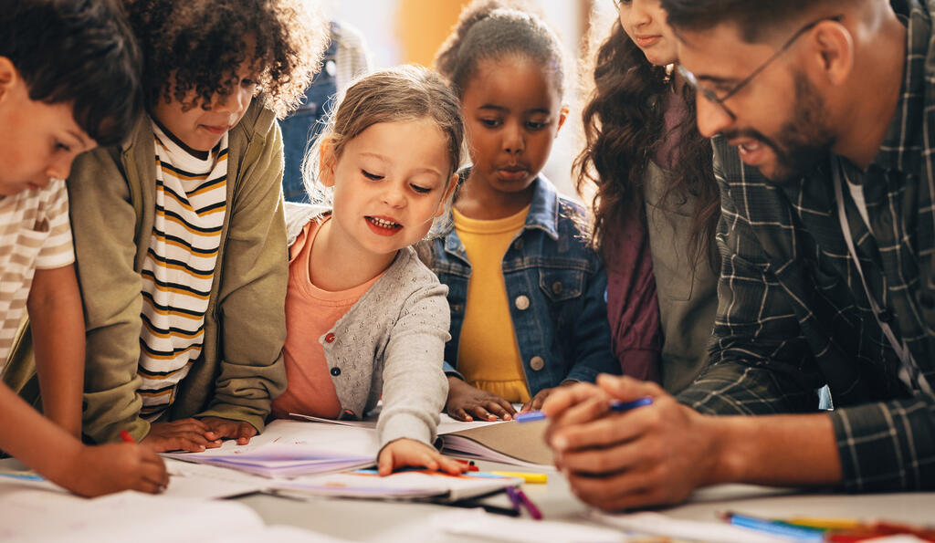 Grundschulkinder und Lehrer um einen Gruppentisch