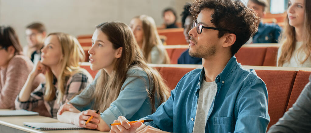 Studierende folgenden den Ausführungen ihres Dozenten in einem Lehrsaal.