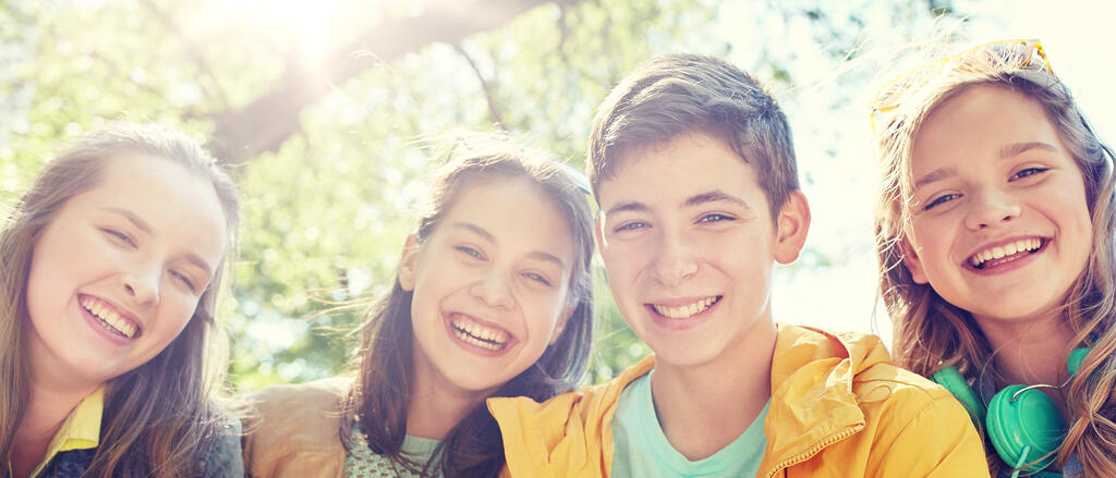 Vier Schülerinnen und Schüler sitzen im Sonnenlicht und strahlen.