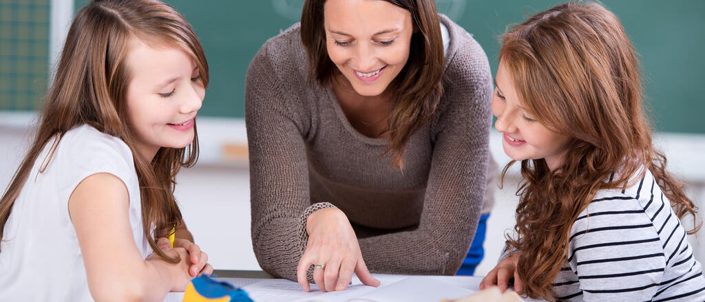 Eine Lehrerin unterstützt zwei Schülerinnen